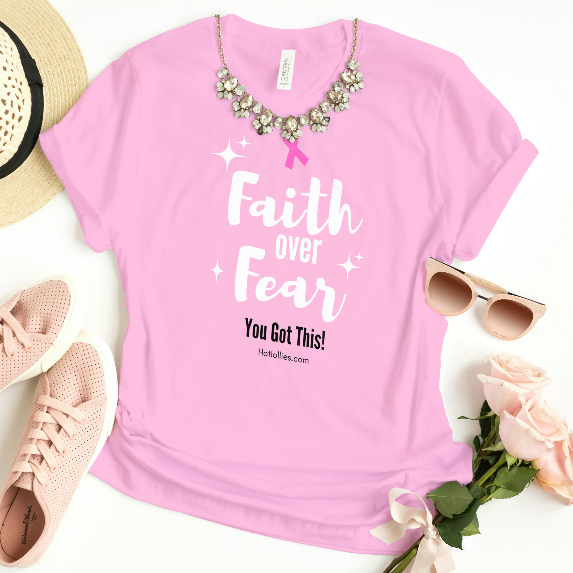 Pink t-shirt with 'Faith over Fear' text, sunglasses, sneakers, and flowers on a white background