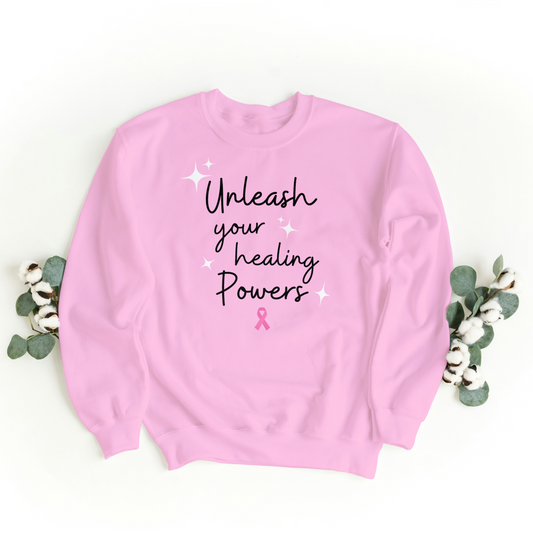 Pink sweatshirt with 'Unleash your healing powers' text and a pink ribbon.