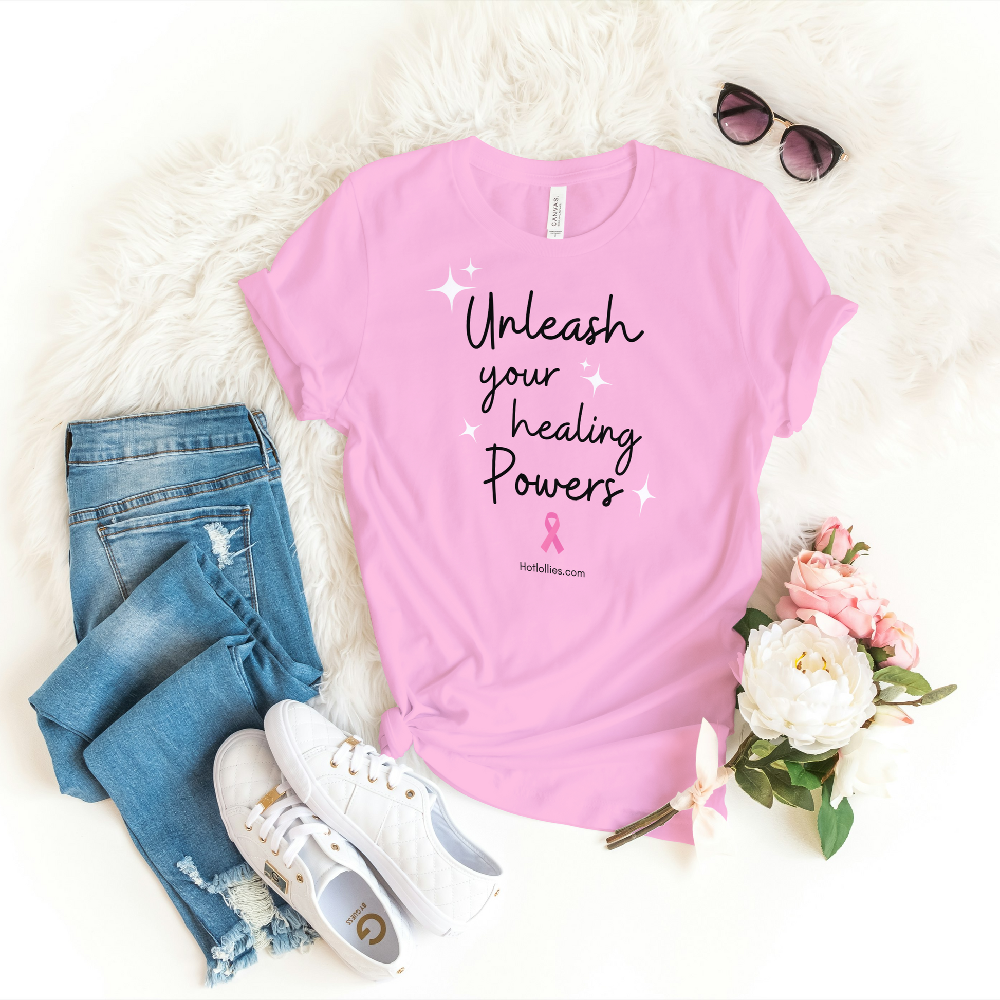 Pink t-shirt with 'Unleash your healing powers' text, jeans, sneakers, and flowers on a white background