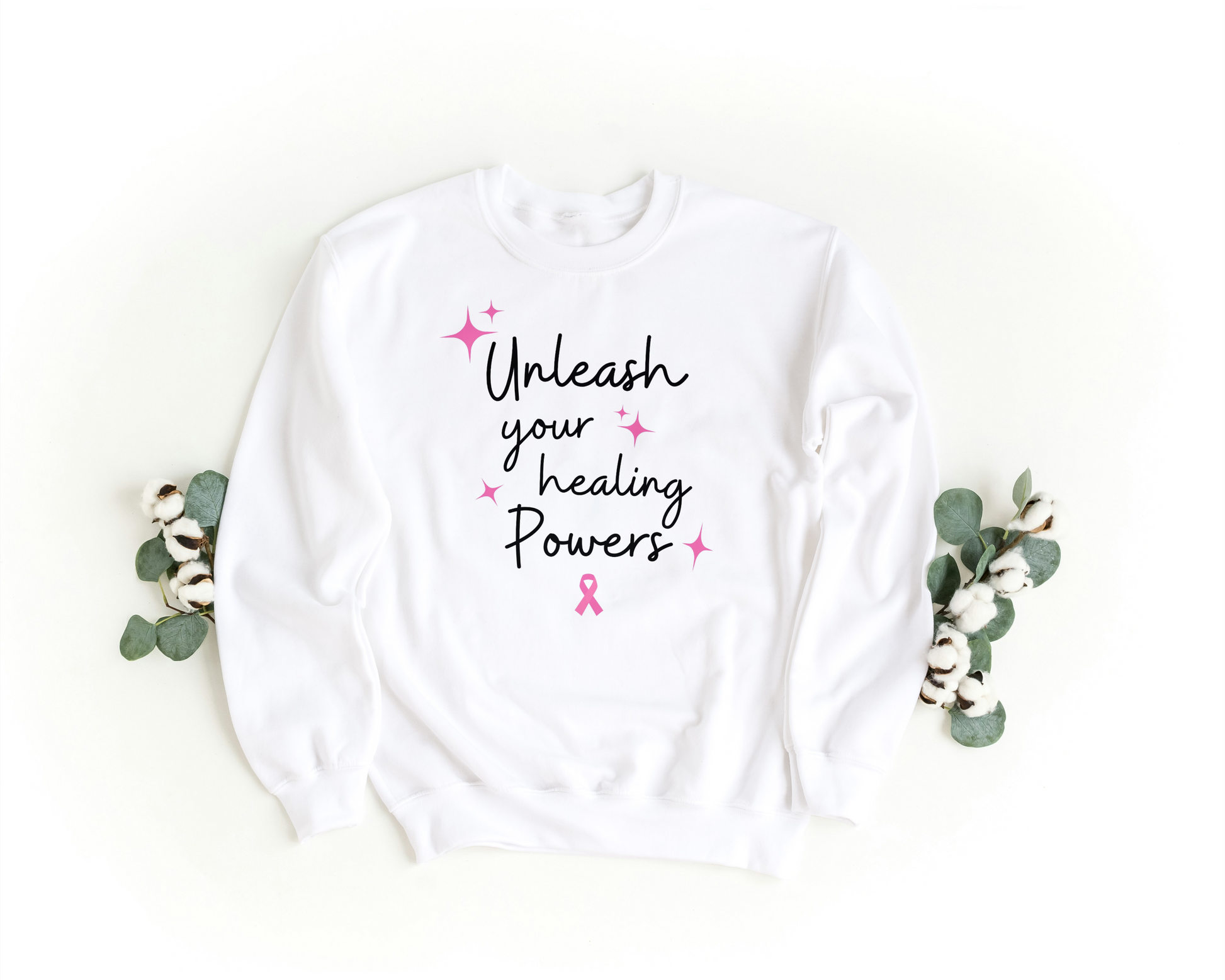 White sweatshirt with 'Unleash your healing powers' text, pink starbursts  and pink ribbon.