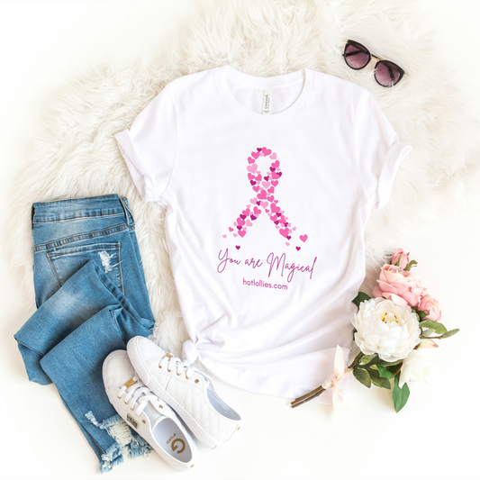 White t-shirt with pink ribbon design and 'You are Magical' text displayed with jeans, sneakers, and flowers.