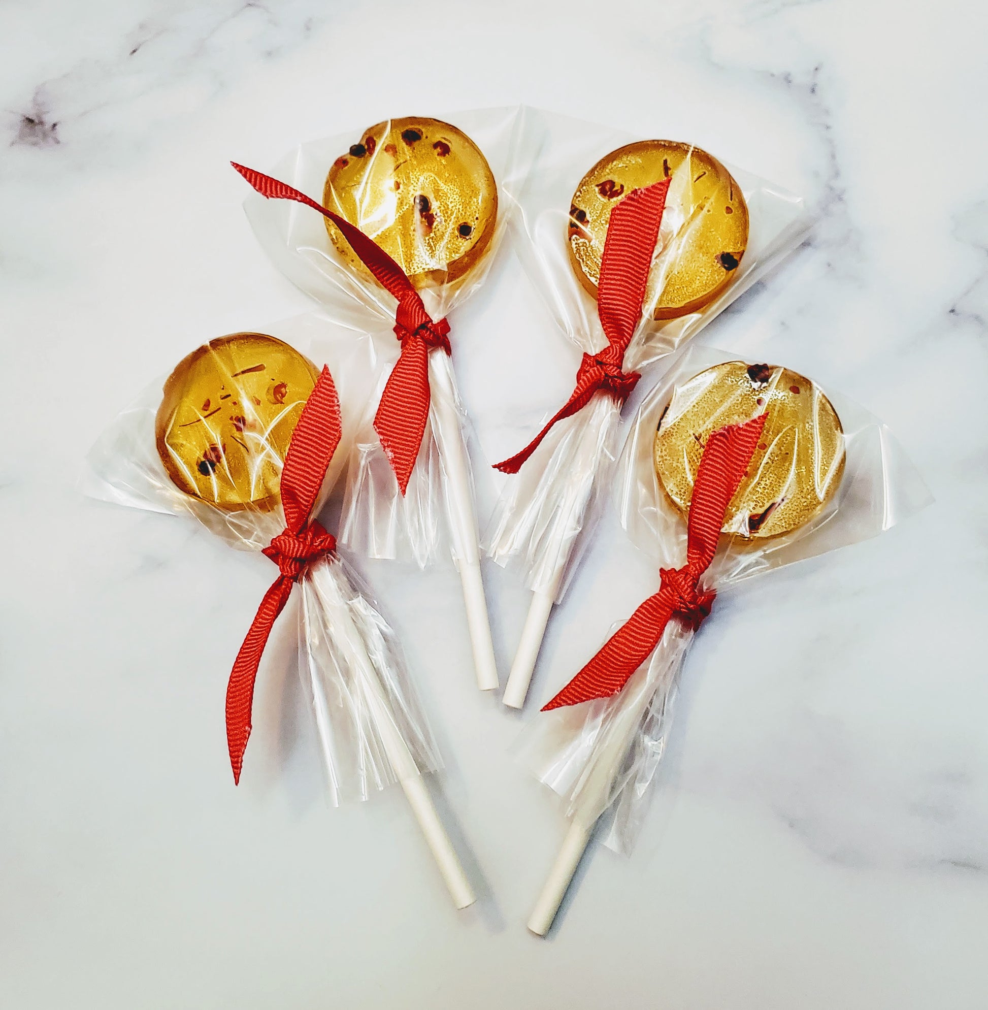 four wrapped saffron and pink peppercorns lollipops