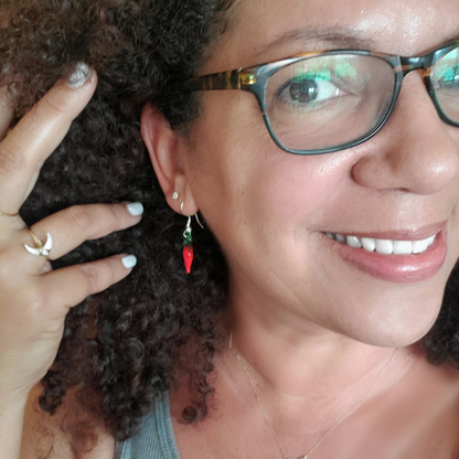 woman wearing glass chile pepper earrings