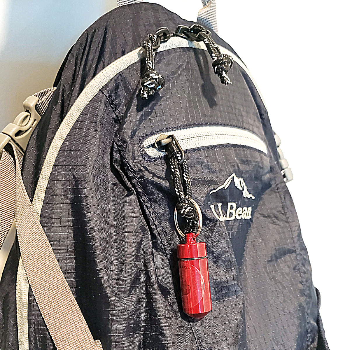 red spice vial keychain on a blue backpack