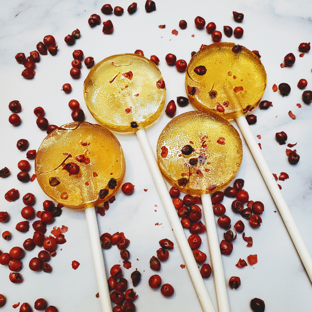 saffron and pink peppercorn lollipops surrounded by pink peppercorns